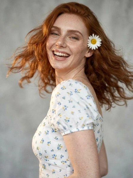 A_woman_with_wavy_red_hair_and_freckles_wearing_wh-1774496559644