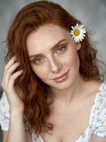 A_woman_with_wavy_red_hair_and_freckles_wearing_wh-1774496563511
